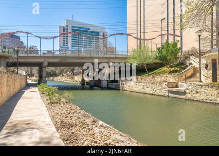 Passerella accanto al fiume vicino al bidge ed edifici a San Antonio, Texas. Passerella in cemento con lampioni e una vista di una scala a destra n Foto Stock