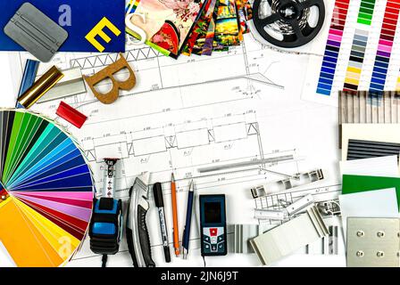 Strumenti e attrezzature per la pubblicità all'aperto. Tavolozza di colori di film, profilo di alluminio e campioni di plastica e strumenti sul disegno del cartellone de Foto Stock