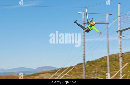 Uomo che guida lungo una zipline al corso di accesso ad alta corda in Islanda Foto Stock