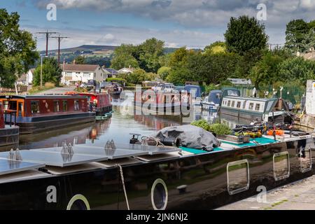 Le chiatte (barche a remi) navigano lungo il Leeds Liverpool Canal a Bingley, West Yorkshire. Altri sono ormeggiati. Questo è sopra i cinque blocchi di sollevamento. Foto Stock