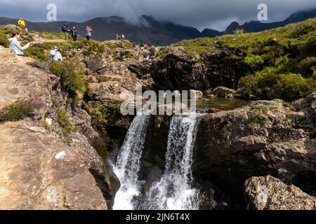 Glenbrittle, Regno Unito - 30 Giugno, 2022: I turisti amano visitare e fare il bagno alle piscine delle fate del fragore del fiume sull'isola di Skye Foto Stock