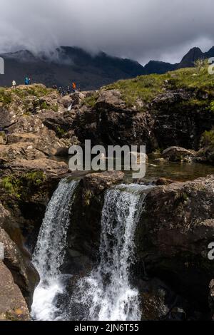 Glenbrittle, Regno Unito - 30 Giugno, 2022: I turisti amano visitare e fare il bagno alle piscine delle fate del fragore del fiume sull'isola di Skye Foto Stock