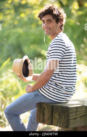 giovane uomo con cuffie e cappello nel parco Foto Stock