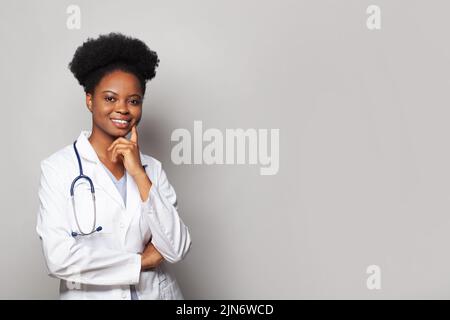 Giovane donna pensante medico in uniforme bianca in piedi su sfondo bianco banner Foto Stock