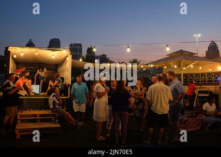 Dubai, Emirati Arabi Uniti - 26 marzo 2016: gli adulti si riuniscono con le bevande mentre il sole tramonta al Food Truck Jam in Emirates Golf Club. Foto Stock