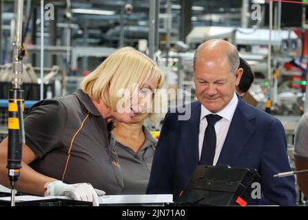 23 maggio 2022, Hessen, Allendorf (Eder): Il cancelliere tedesco OLAF Scholz (SPD) avvita l'ultima vite in una pompa di calore sotto la guida di un dipendente Viessmann. Scholz ha appreso informazioni sulle pompe di calore e sulle soluzioni per il clima verde presso l'azienda a conduzione familiare Viessmann. Foto: Nadine Weigel/dpa Foto Stock