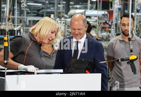 23 maggio 2022, Hessen, Allendorf (Eder): Il cancelliere tedesco OLAF Scholz (SPD) avvita l'ultima vite in una pompa di calore sotto la guida di un dipendente Viessmann. Scholz ha appreso informazioni sulle pompe di calore e sulle soluzioni per il clima verde presso l'azienda a conduzione familiare Viessmann. Foto: Nadine Weigel/dpa Foto Stock