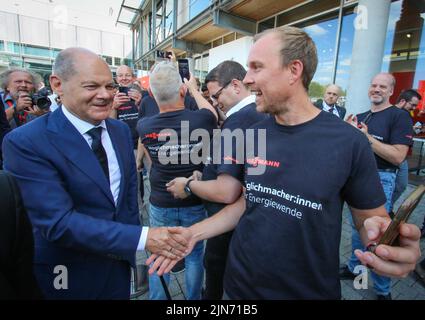 23 maggio 2022, Hessen, Allendorf (Eder): I dipendenti di Viessmann danno il benvenuto al cancelliere tedesco OLAF Scholz (SPD - l) nella sede della società a conduzione familiare Hessian. Scholz ha appreso informazioni sulle pompe di calore e sulle soluzioni per il clima verde presso l'azienda Viessmann. Foto: Nadine Weigel/dpa Foto Stock