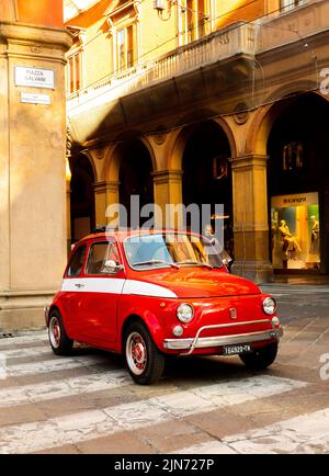 Auto italiana classica parcheggiata su strada nella città italiana di Bologna. Fiat 500. Rosso con finitura bianca. Foto Stock