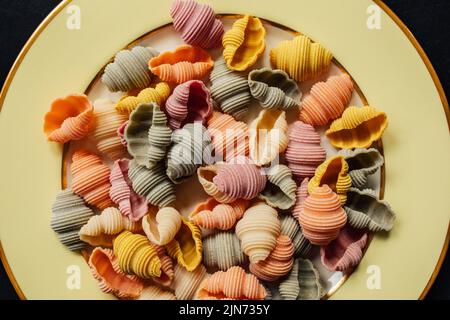 Conchiglie di Conchiglie di Conchiglioni di mare secco Pasta colorata, spinaci, barbabietole, curcuma e paprika per colorare la pasta verde, rosa, giallo, arancio Foto Stock