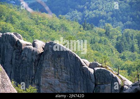 Enormi formazioni rocciose di massi alte in montagna con alberi in crescita in estate giorno di sole Foto Stock