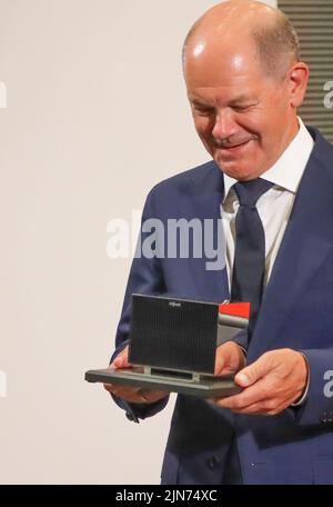 09 agosto 2022, Hessen, Allendorf (Eder): Il cancelliere tedesco OLAF Scholz (SPD) esamina la piccola pompa di calore in miniatura che ha ricevuto in regalo durante la sua visita alla società Viessmann. Scholz ha appreso informazioni sulle pompe di calore e sulle soluzioni per il clima verde presso l'azienda a conduzione familiare Viessmann. Foto: Nadine Weigel/dpa Foto Stock