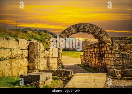 Ingresso stadio - muri in pietra e arco che entrano nel campo dove i primi giochi di Pah Hellenic si sono svolte a Olympia Grecia al tramonto. Foto Stock