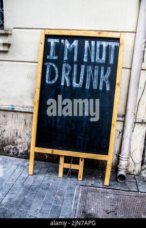 Alzarsi in piedi cartello cartellone pieghevole appeso contro parete grungy e drenaggio da marciapiede con im non ubriaco scritto ordinatamente su di esso con gesso. Foto Stock