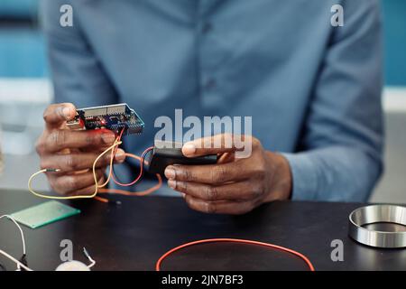 Primo piano del giovane nero che tiene il circuito stampato mentre costruisce il robot, spazio di copia Foto Stock