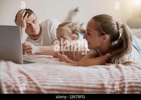 Primo piano della famiglia felice divertirsi insieme guardando i cartoni animati online su un portatile si trova sul divano a casa Foto Stock