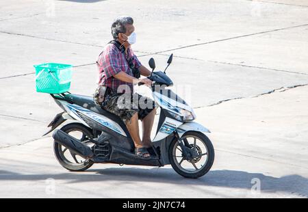 SAMUT PRAKAN, THAILANDIA, 09 2022 GIUGNO, Un uomo con maschera facciale corre una motocicletta nella strada della città Foto Stock