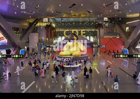 Sala partenze all'aeroporto internazionale di Hamad, Doha, Qatar di notte con la grande statua dell'orso delle lampade dell'artista svizzero Urs Fischer e # Qatar 2022 Foto Stock