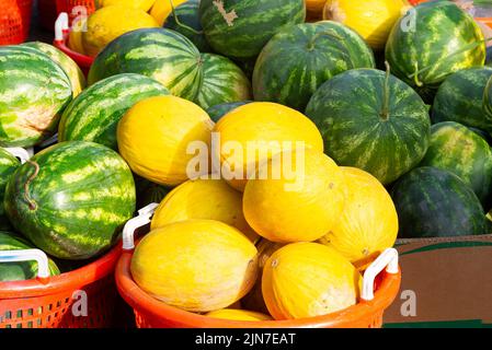 Meloni e angurie freschi e maturi in vendita presso un mercato locale all'aperto Foto Stock