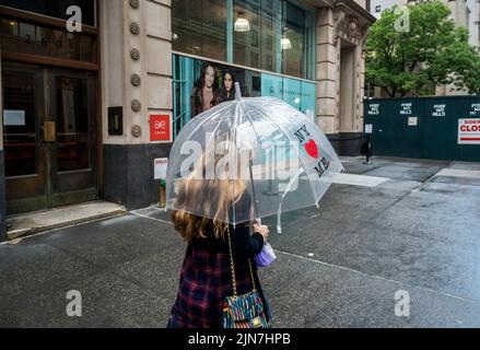 Le persone si contendono con un torrential downpour nel quartiere Nomad di New York domenica 7 agosto 2022. Il calore e l'umidità senza condensa sono attesi questa settimana quando le temperature aumentano a metà degli anni '90 con l'umidità che induce sudore aggiunta alla miscela supia. (© Richard B. Levine) Foto Stock