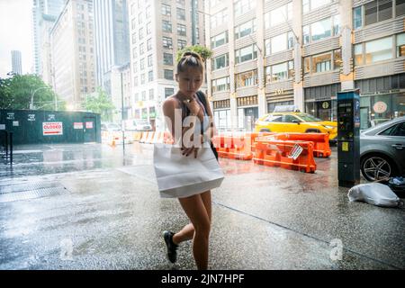 Le persone si contendono con un torrential downpour nel quartiere Nomad di New York domenica 7 agosto 2022. Il calore e l'umidità senza condensa sono attesi questa settimana quando le temperature aumentano a metà degli anni '90 con l'umidità che induce sudore aggiunta alla miscela supia. (© Richard B. Levine) Foto Stock