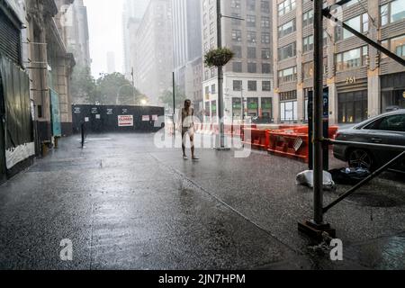 Le persone si contendono con un torrential downpour nel quartiere Nomad di New York domenica 7 agosto 2022. Il calore e l'umidità senza condensa sono attesi questa settimana quando le temperature aumentano a metà degli anni '90 con l'umidità che induce sudore aggiunta alla miscela supia. (© Richard B. Levine) Foto Stock