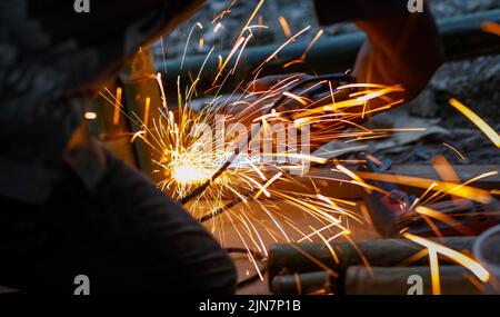 Scintille volanti provenienti da un smerigliatore angolare utilizzato di notte Foto Stock