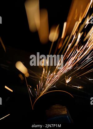 Scintille volanti provenienti da un smerigliatore angolare utilizzato di notte Foto Stock