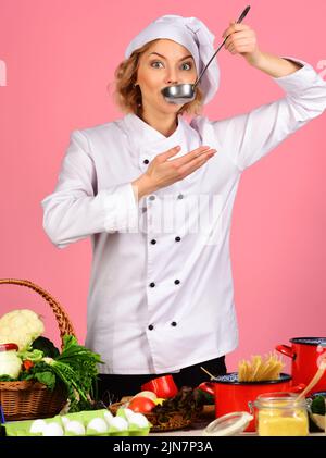 Cuoco femminile in uniforme bianca con cucchiaio per mestolo. Cucina e cucina professionale. Preparazione del cibo. Foto Stock