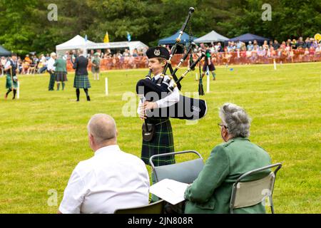 Tomintoul Highland games 2022, giovane ragazzo suona le cornamuse ed è giudicato da due giudici anziani, Scozia,UK,estate 2022 Foto Stock