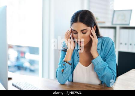 Qui viene che la tensione testarda emicrania ancora. Una giovane donna d'affari che osserva stressata fuori mentre lavora in un ufficio. Foto Stock