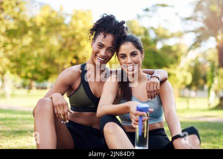 Orgoglioso del mio amico. Ritratto ritagliato di due belle giovani donne sedute l'una accanto all'altra e sorridenti mentre si trovano nel parco. Foto Stock