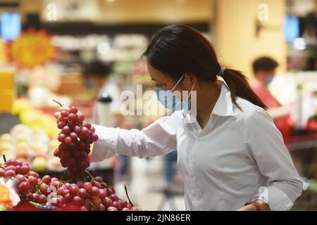 HANGZHOU, CINA - 10 AGOSTO 2022 - i clienti scelgono l'uva in un supermercato a Hangzhou, provincia di Zhejiang, Cina, 10 agosto 2022. I prezzi al consumo sono aumentati Foto Stock