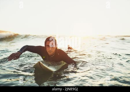 Youll spesso mi trova vicino alle onde. Ritratto di un giovanotto che si addita su una tavola da surf in mare. Foto Stock