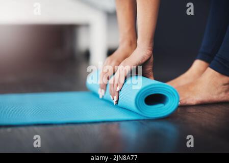 Shes ben attrezzata per la sua sessione. Una giovane donna irriconoscibile che rotola il suo tappeto yoga nella sua camera da letto. Foto Stock