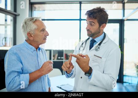 Guidandolo attraverso le fasi di recupero. Un medico che consulta un paziente anziano maschio nel suo ufficio. Foto Stock