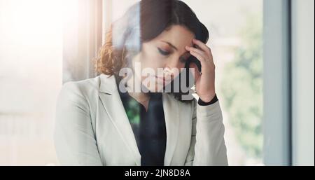Questa sensazione è più di quanto possa gestire: Una giovane e attraente donna d'affari che si sente stressata sul lavoro. Foto Stock