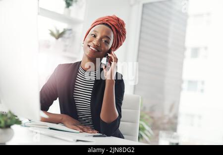 Grazie per avermi chiamato indietro. Una giovane donna d'affari attraente che fa una telefonata mentre siede alla sua scrivania in ufficio. Foto Stock