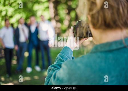 Un fotografo di nozze scatta foto degli ospiti della sposa e dello sposo in natura in una giornata di sole Foto Stock