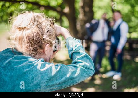 Un fotografo di nozze scatta foto degli ospiti della sposa e dello sposo in natura in una giornata di sole Foto Stock