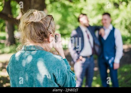 Un fotografo di nozze scatta foto degli ospiti della sposa e dello sposo in natura in una giornata di sole Foto Stock