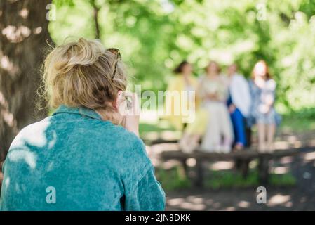 Un fotografo di nozze scatta foto degli ospiti della sposa e dello sposo in natura in una giornata di sole Foto Stock