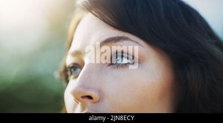 Parla la bellezza con i suoi occhi. Primo piano di un'attraente giovane donna che guarda via in un parco pubblico. Foto Stock