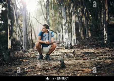 Un giovane spensierato che si prende una breve pausa dal trekking su una montagna durante il giorno. Foto Stock