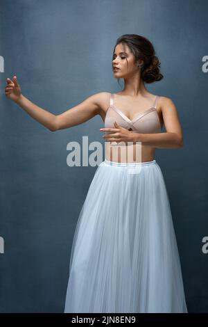 Espressione di sé attraverso la danza. Studio girato di una giovane ballerina femminile attraente che si posa su uno sfondo grigio. Foto Stock