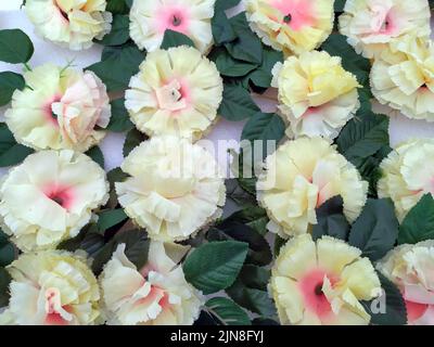 Fiori artificiali di colore giallo chiaro con foglie verdi Foto Stock