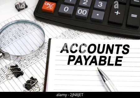 Concetto aziendale. Sul tavolo c'è una lente d'ingrandimento, una calcolatrice, una penna e un quaderno con l'iscrizione - Accounts Payable Foto Stock