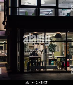 Un caffè accogliente con interni moderni e gente che chiacchiera sotto la luce soffusa a Middlesbrough Foto Stock