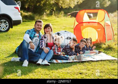 Famiglia che passa il tempo insieme. Quattro bambini e genitori all'aperto in coperta da picnic. Grande famiglia in maglia a scacchi. Foto Stock