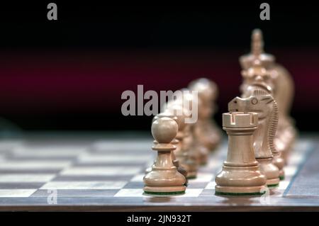 Foto ravvicinata di pezzi di scacchi su una scacchiera con uno sfondo sfocato. Rook, cavaliere e pedina in primo piano. Foto Stock